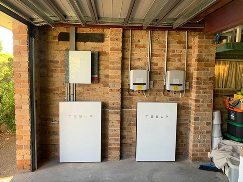 Two Tesla Powerwall batteries installed on a garage wall